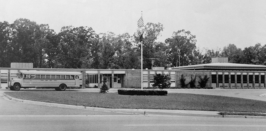 Black and white photograph of the front exterior of Lake Anne Elementary School taken in 1972. A school bus is parked in front of the building. 