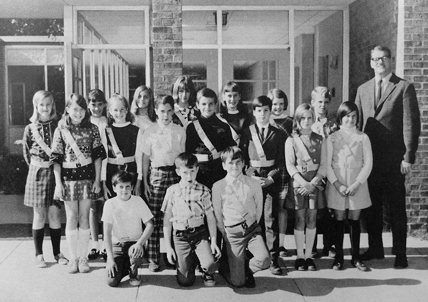 Black and white yearbook photograph of the Lake Anne's Safety Patrol and the teacher sponsor. 17 children are pictured, primarily girls, and they are all wearing the distinctive sash and belt given to patrols. 