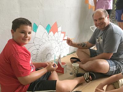 A student and his dad enjoy working on the mural.